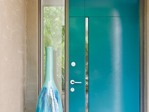 Exterior blue doorway with neutral painted brick and silver furnishings and vase